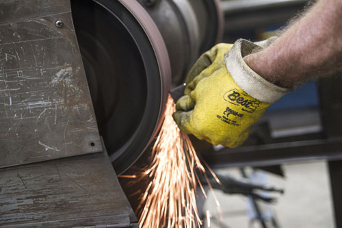 Sparks fly as a man shaves a piece of metal.