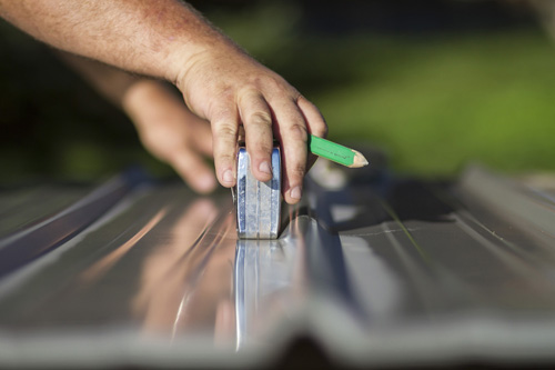 Hands use pencil and measuring tape to make a cut onsite in Saline, Michigan