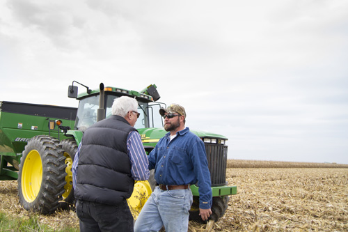 Men shake hands in a corn field for website photo shoot in southeast Michigan
