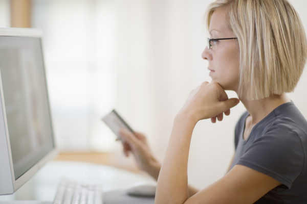 Serious woman shopping online with credit card making purchase decision