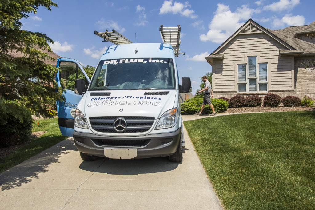 Tech walks on sidewalk to chimney cleaning van.