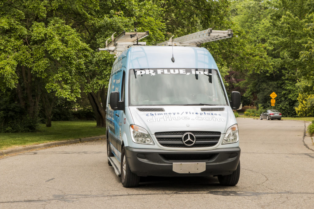 Van in front of trees with ladder rack.