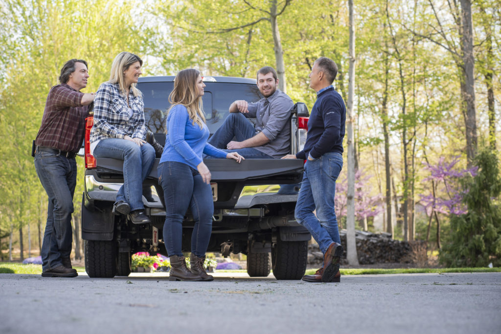 People stand and talk, gathered around a work truck.